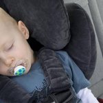 Ребенок сидит в автокресле с закрытыми глазами